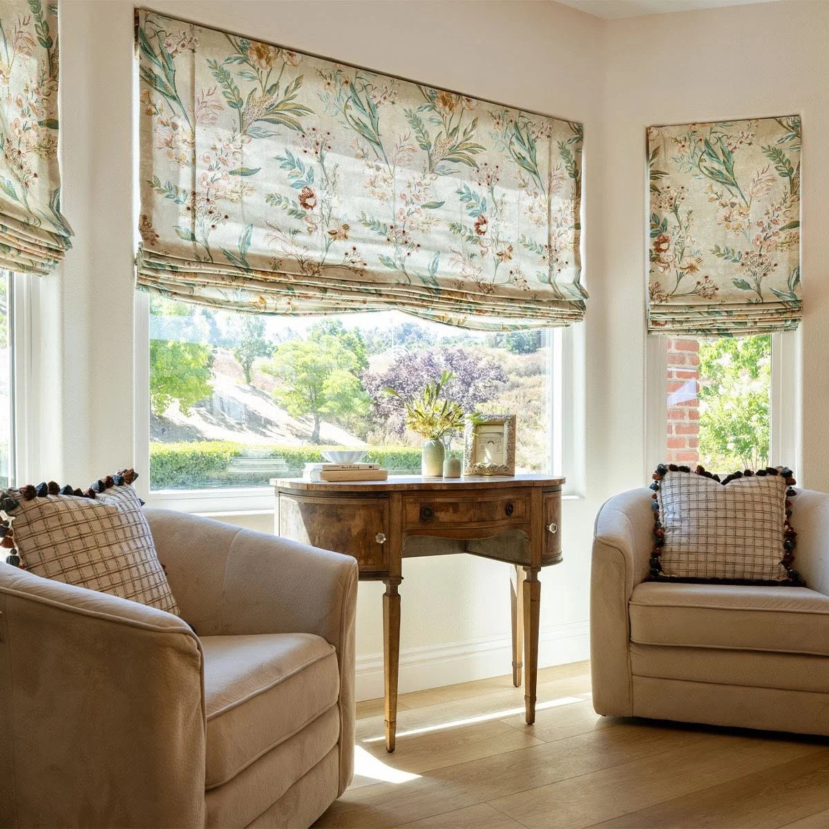 Floral relaxed Roman shades on a bay window, custom made through Window Coverings by Julie