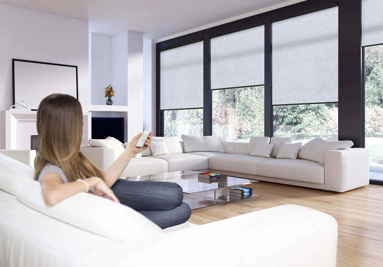 motorized shades by julie Woman using a remote to control motorized shades in a bright living room, available from Window Coverings by Julie